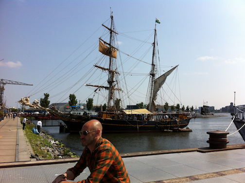 A bicylist on his way to ferry to central Amsterdam on other side of pirate ship, I mean Tres Hombres